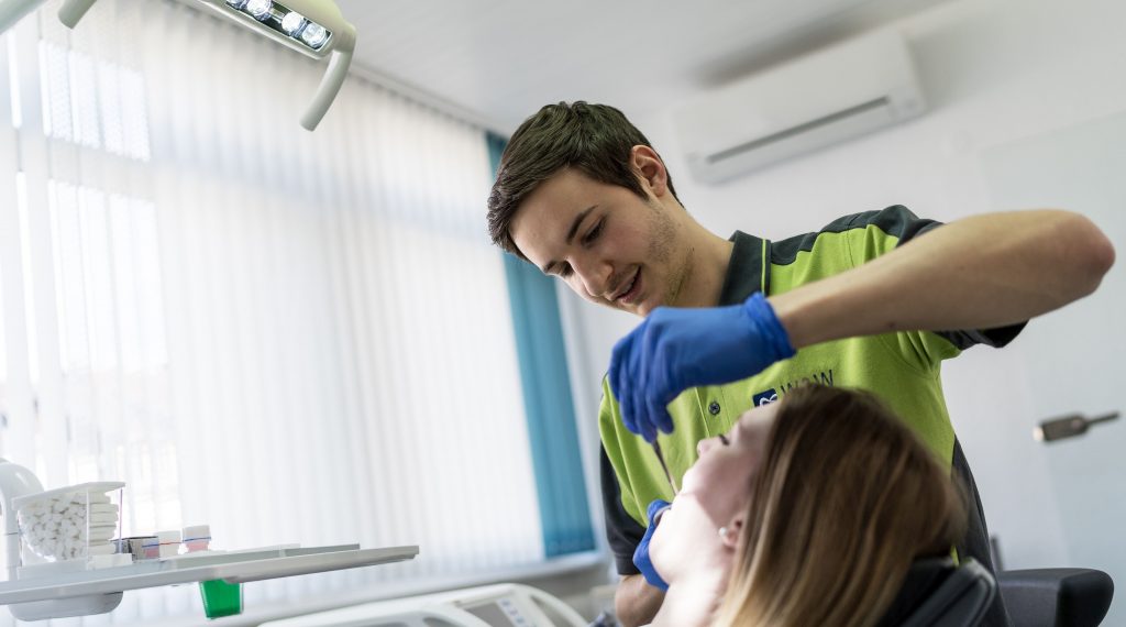 Zahnarzt untersucht den Zahnersatz einer Patientin